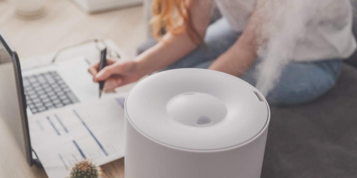 humidifier mists into the air while someone uses a computer