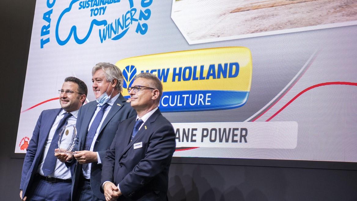 3 peple stand with an Award in front of a sign that reads: New Holland Culture