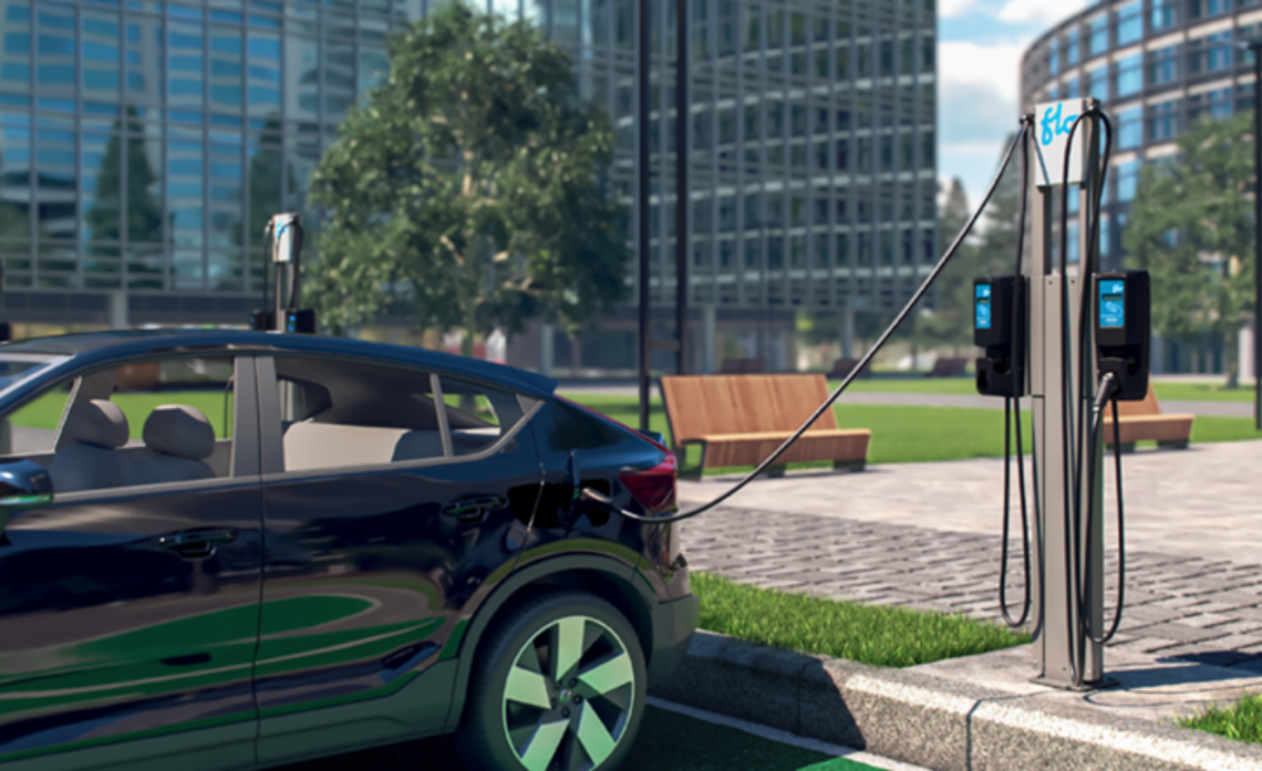 a vehicle plugged in to a charging station, buildings in the background