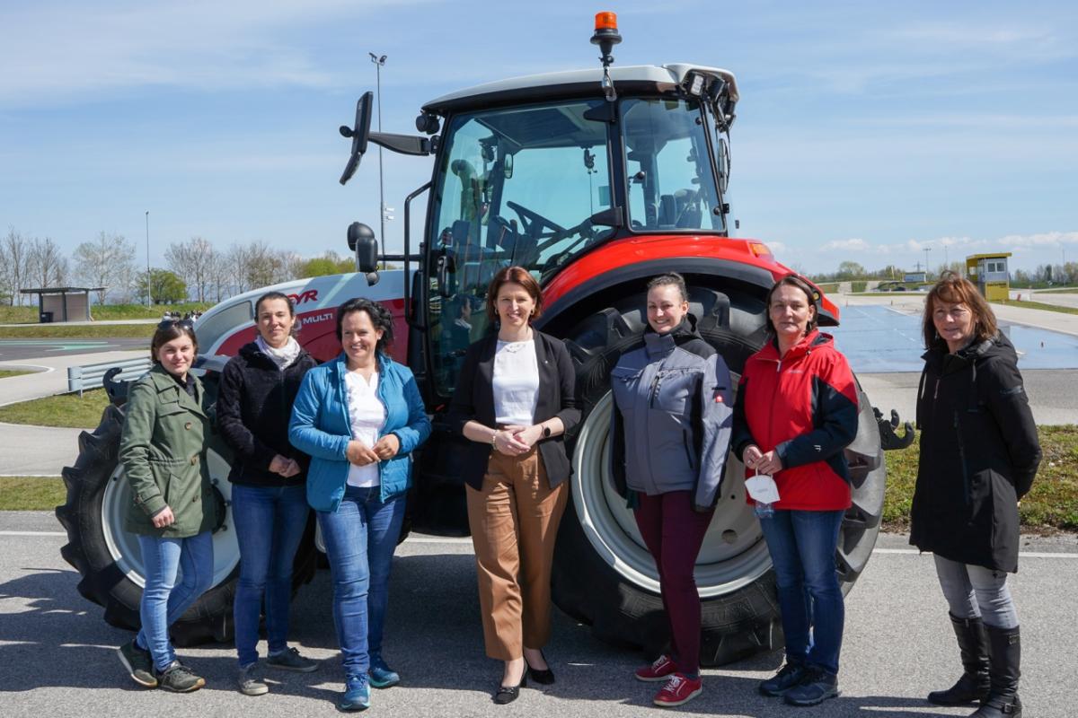 Women students stand in from of a tractor