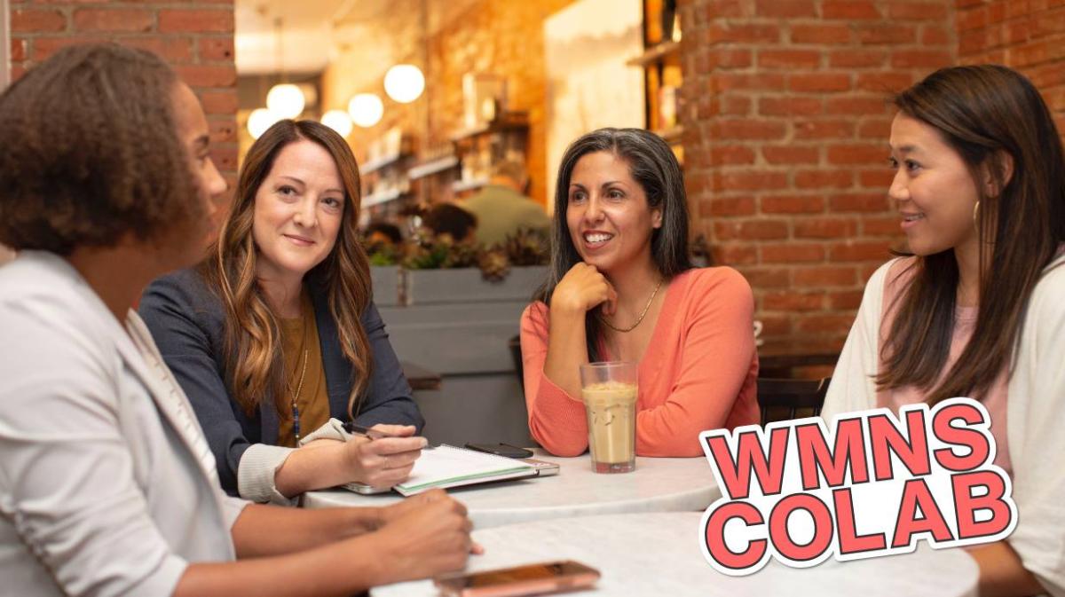 Women gathered around a table with the "Woman's Colab" logo in the bottom corner