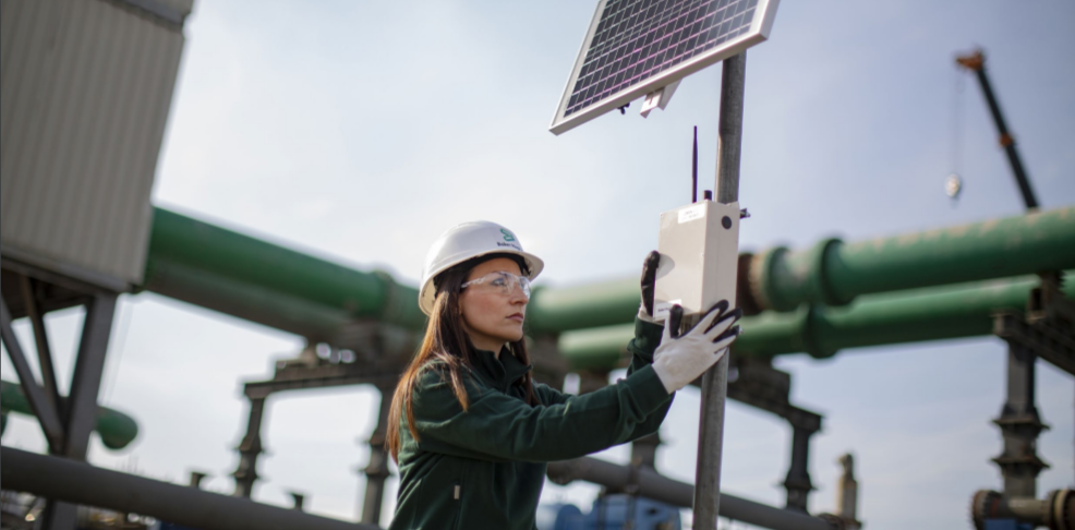 a worker in a hard hat and gloves works on a solar panel 