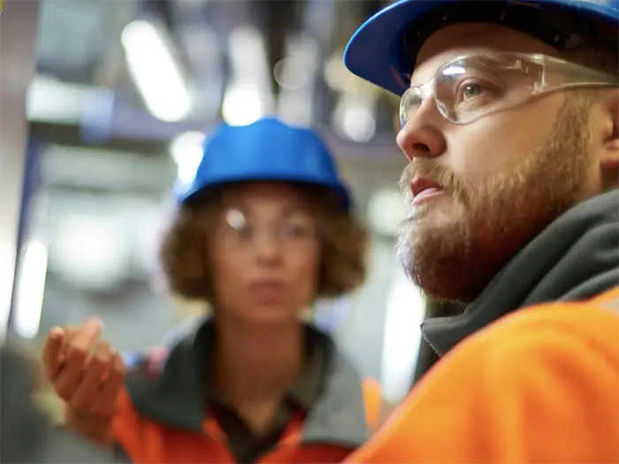 2 people wearing hardhats and safety glasses